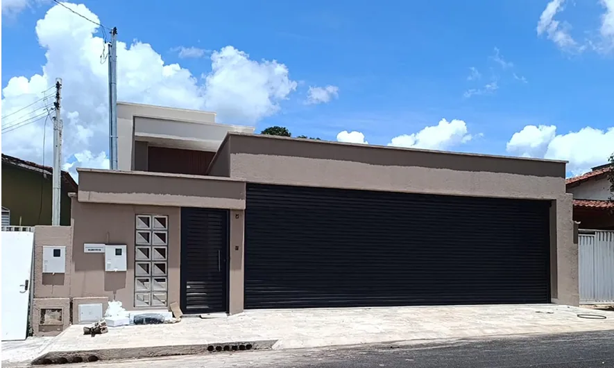 Fachada ampla com porta de enrolar preta